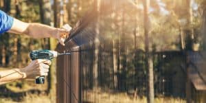 Fencing worker installing metal wire mesh fence panel